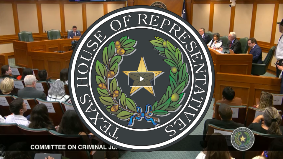 View of a Texas House of Representatives committee hearing room with people seated at desks and a large Texas House seal overlay in the center. The room has wooden paneling and a panel of officials at the front.