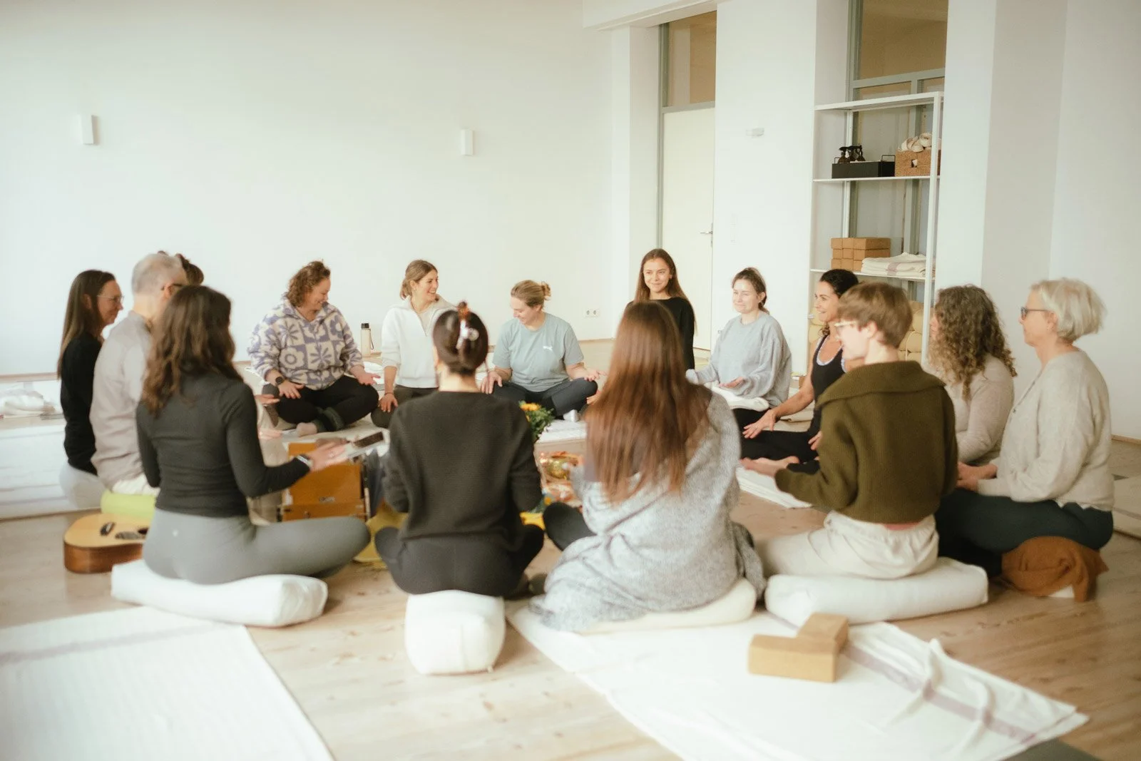 Saskia Schreiber sitzt mit einer Gruppe Frauen im Rahmen ihrer Yin Yoga Ausbildung im Kreis auf Kissen auf dem Boden.