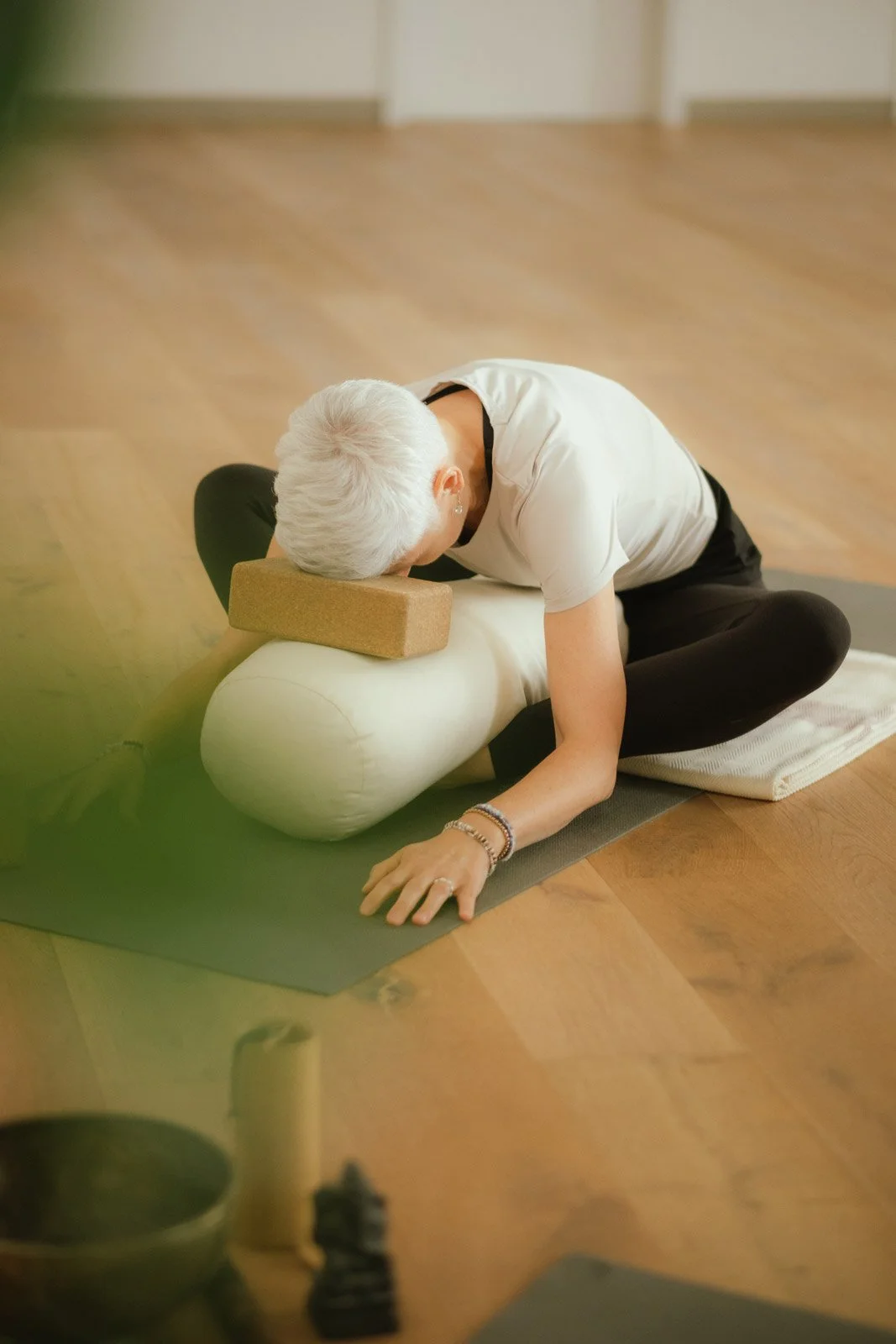 Eine Klientin von Saskia Schreiber in einer Yin Yoga Pose, gestützt durch Bolster und Block.
