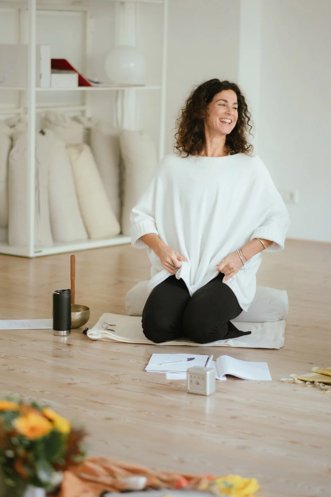 Saskia Schreiber lachend und gelöst auf einer Decke in einem schönen Yoga Raum während ihr Yin Yoga Ausbildung.