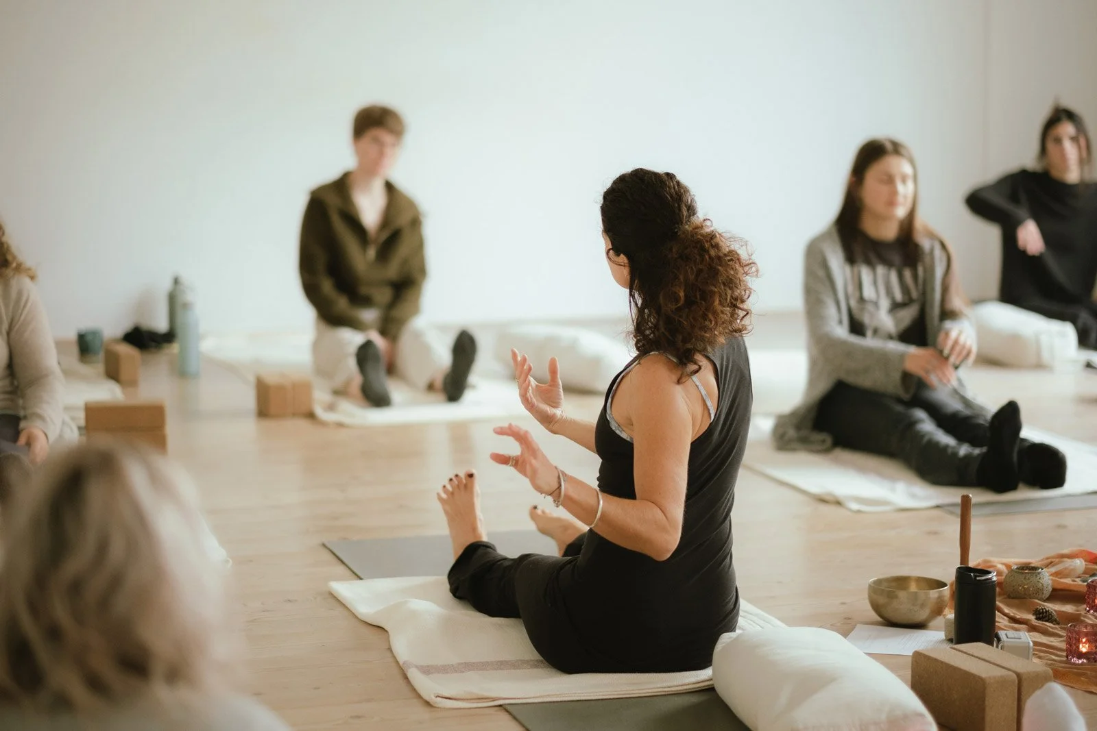 Yogalehrerin in dunkler Kleidung beim Unterrichten im Rahmen einer Yin Yoga Ausbildung.