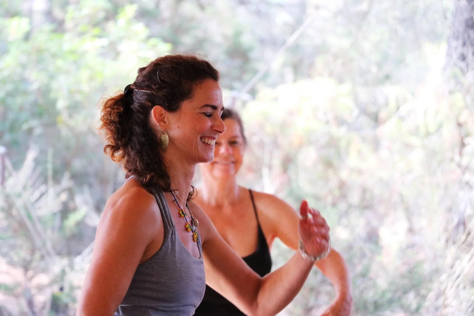 Saskia Schreiber im Rahmen einer Yoga Stunde mit lachender Teilnehmerin im Hintergrund.