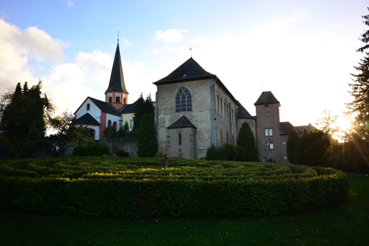 Blick auf das Kloster Steinfeld in der Eifel mit gepflanztem Labyrinth im Vordergrund.