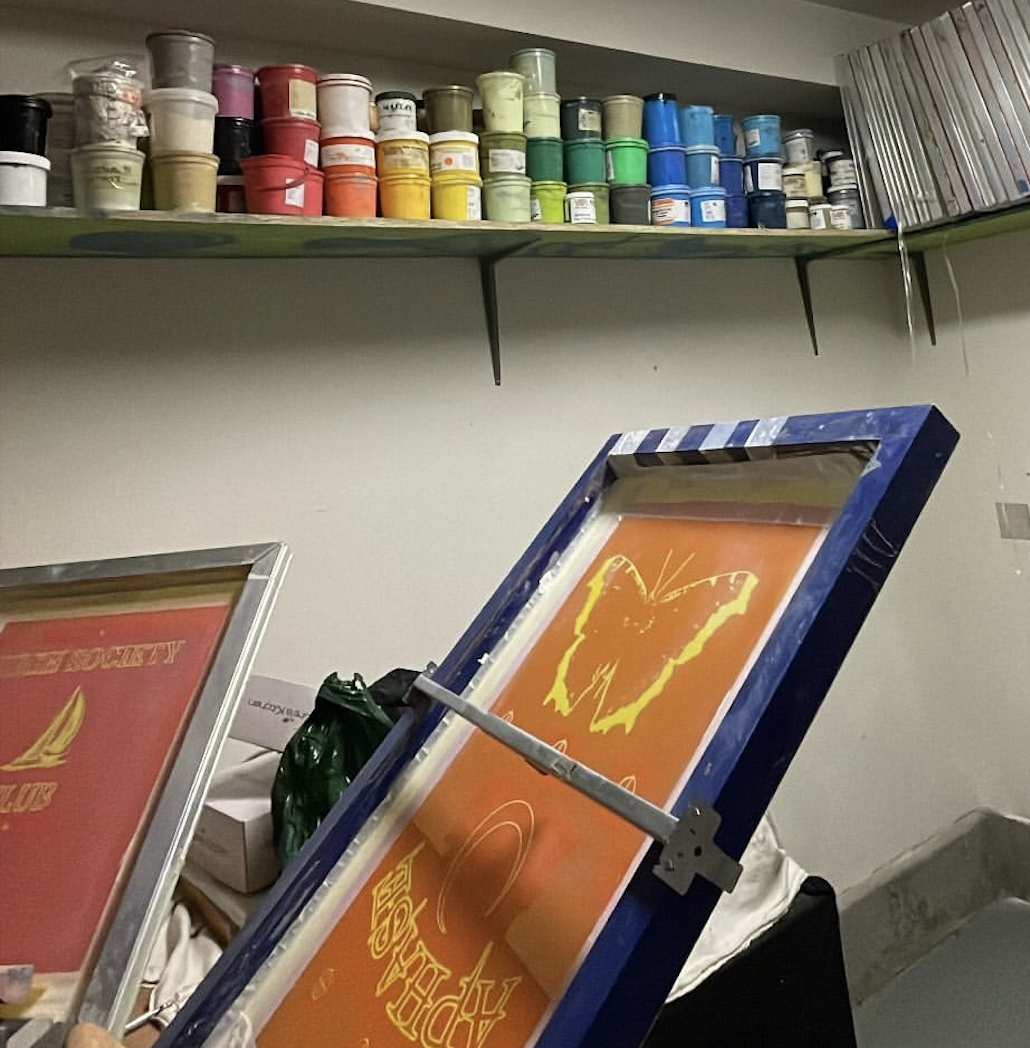 Painted artwork depicting an orange butterfly on an orange background, with the phrase 'HAPPY ART' written in yellow, inside a blue frame.