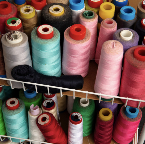 Colorful spools of sewing thread organized on a craft table.