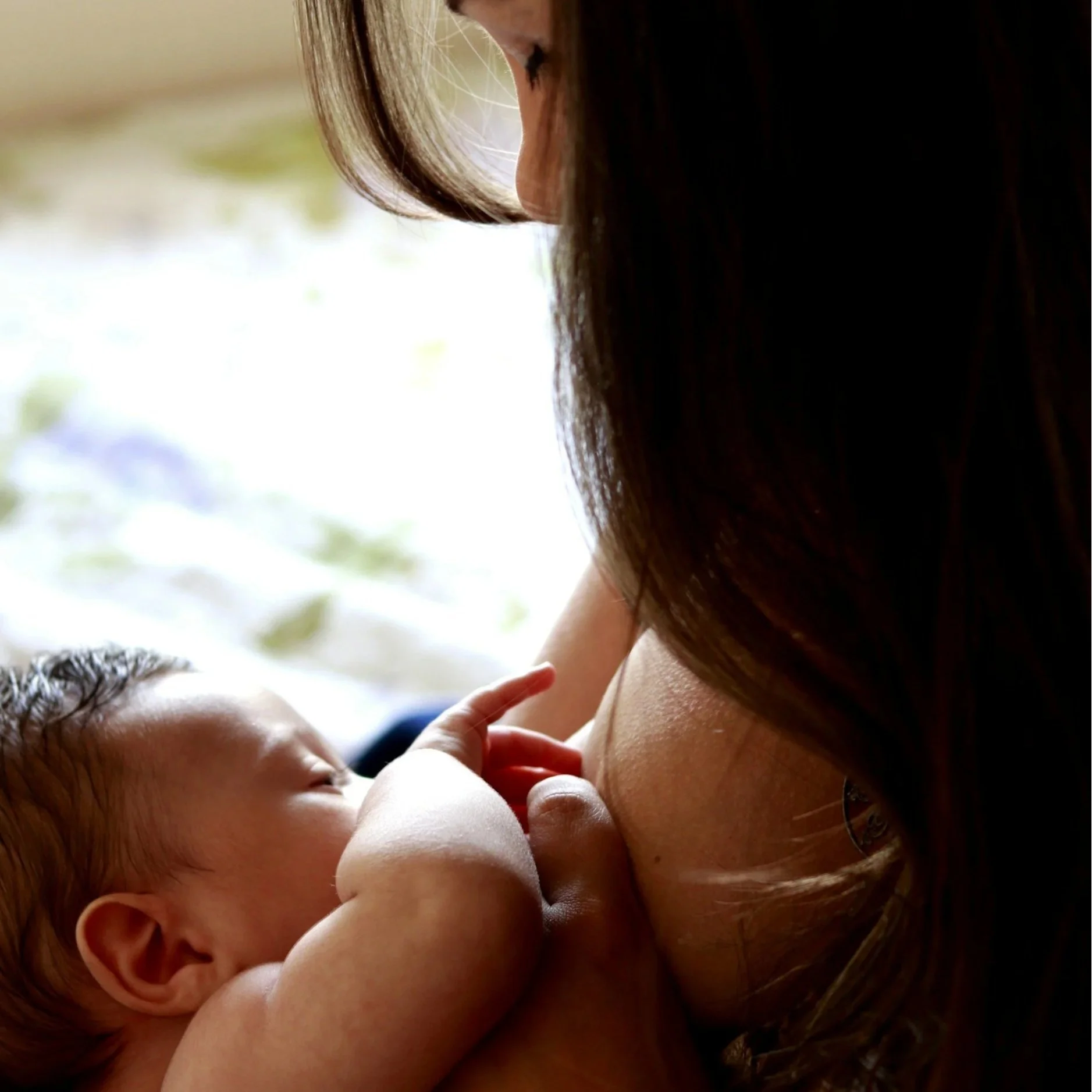 A woman with long hair breastfeeding a baby.
