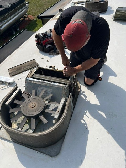 Man working on an air conditioning unit on a rooftop.