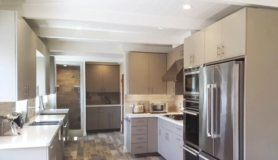 Modern kitchen with gray cabinets, stainless steel appliances, and a wood-look tiled floor.