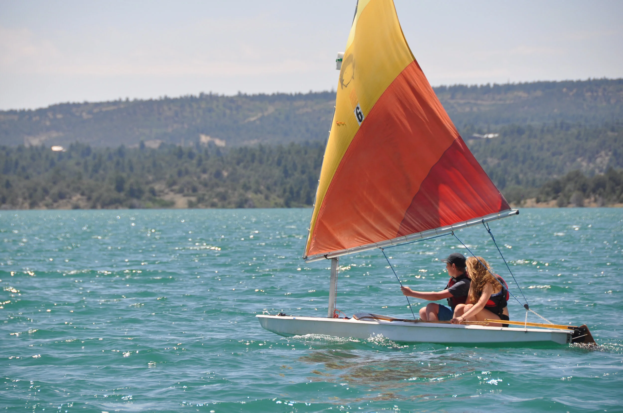 Two children sailing a small boat at summer camp.