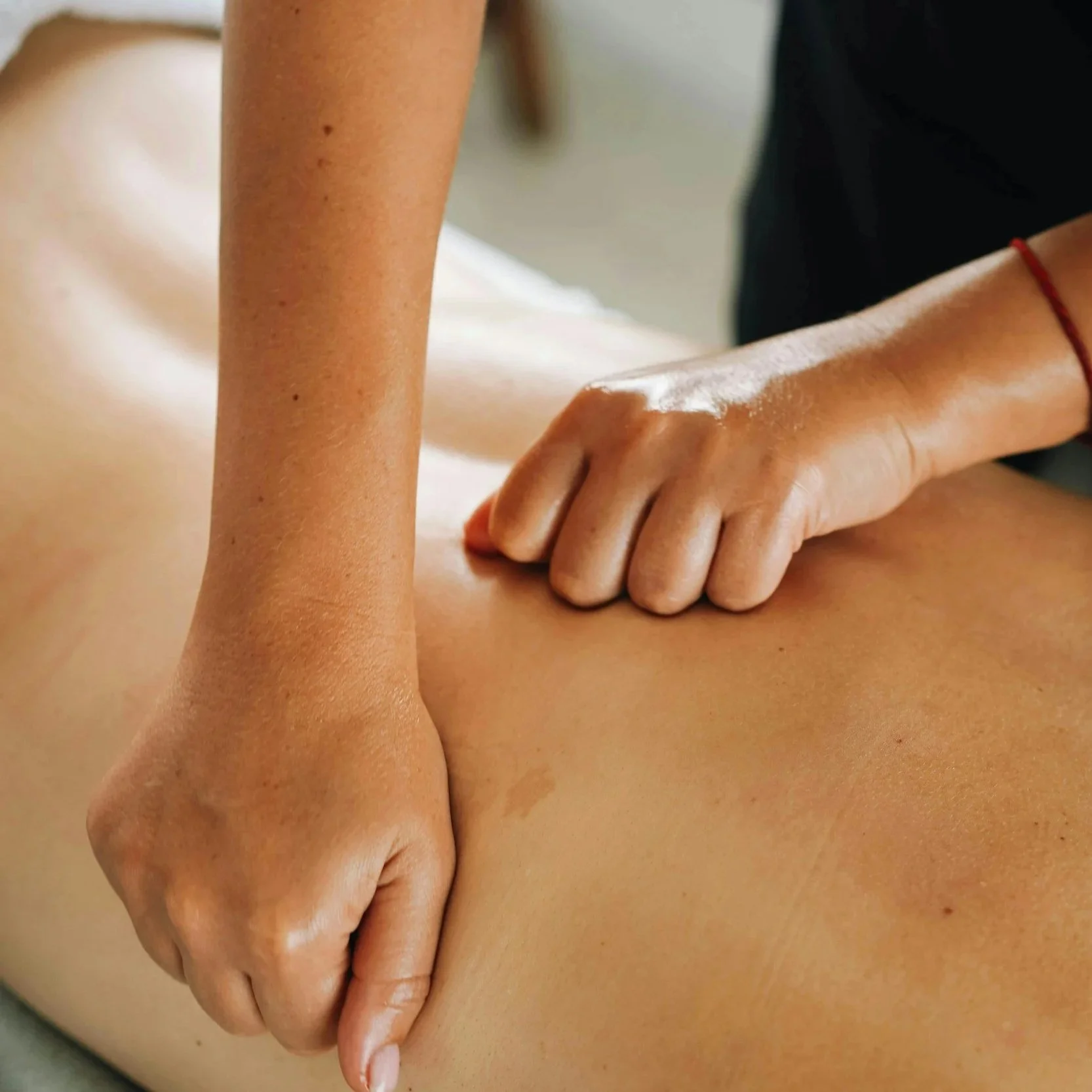 Close-up of a person receiving a massage, focusing on hands applying pressure on the back.