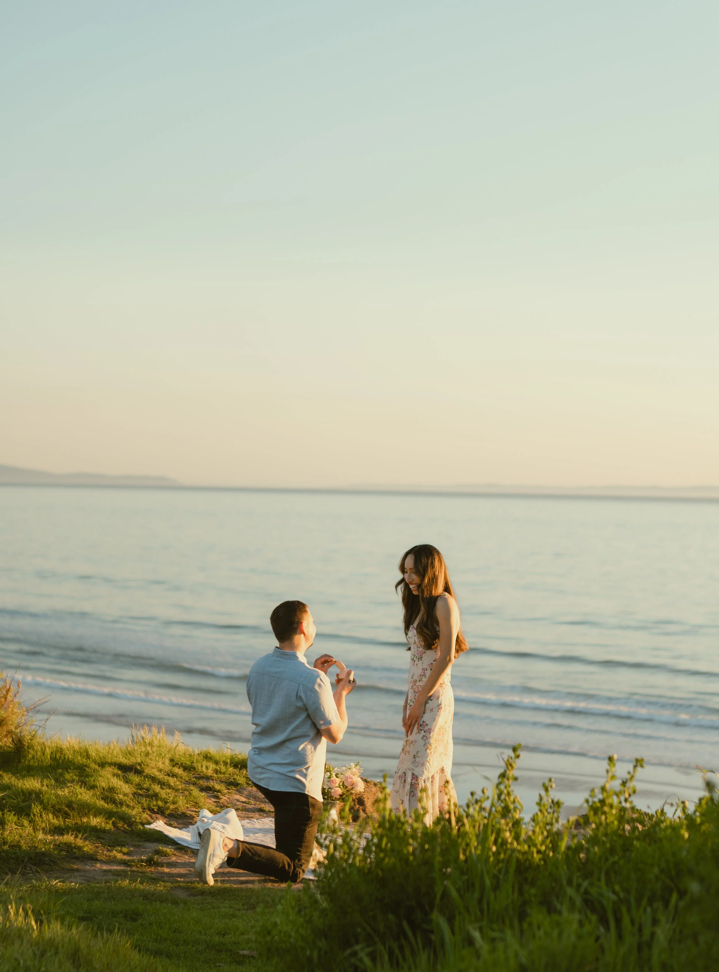 A man proposing to a woman on a beach at sunset.