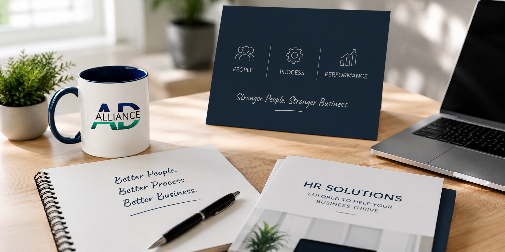 Business workspace with a potted plant, a coffee mug with 'AD Alliance' logo, a blue informational sign about people, process, and performance, a notebook with the text 'Better People. Better Process. Better Business.', a brochure titled 'HR Solutions', a laptop, and a pen on a wooden desk.