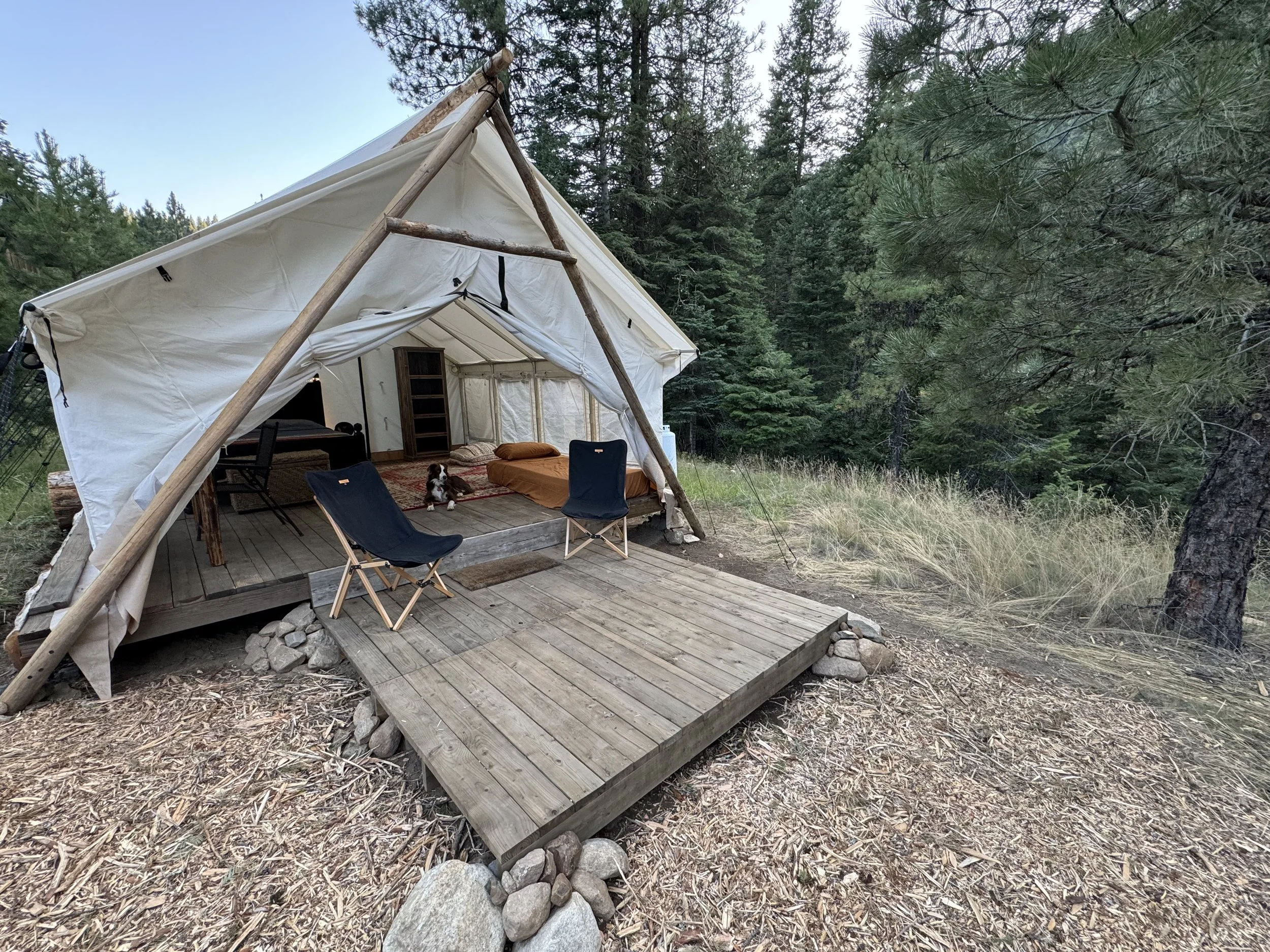 Large wall tent with wood floor, queen-size bed, desk and can sleep a family.