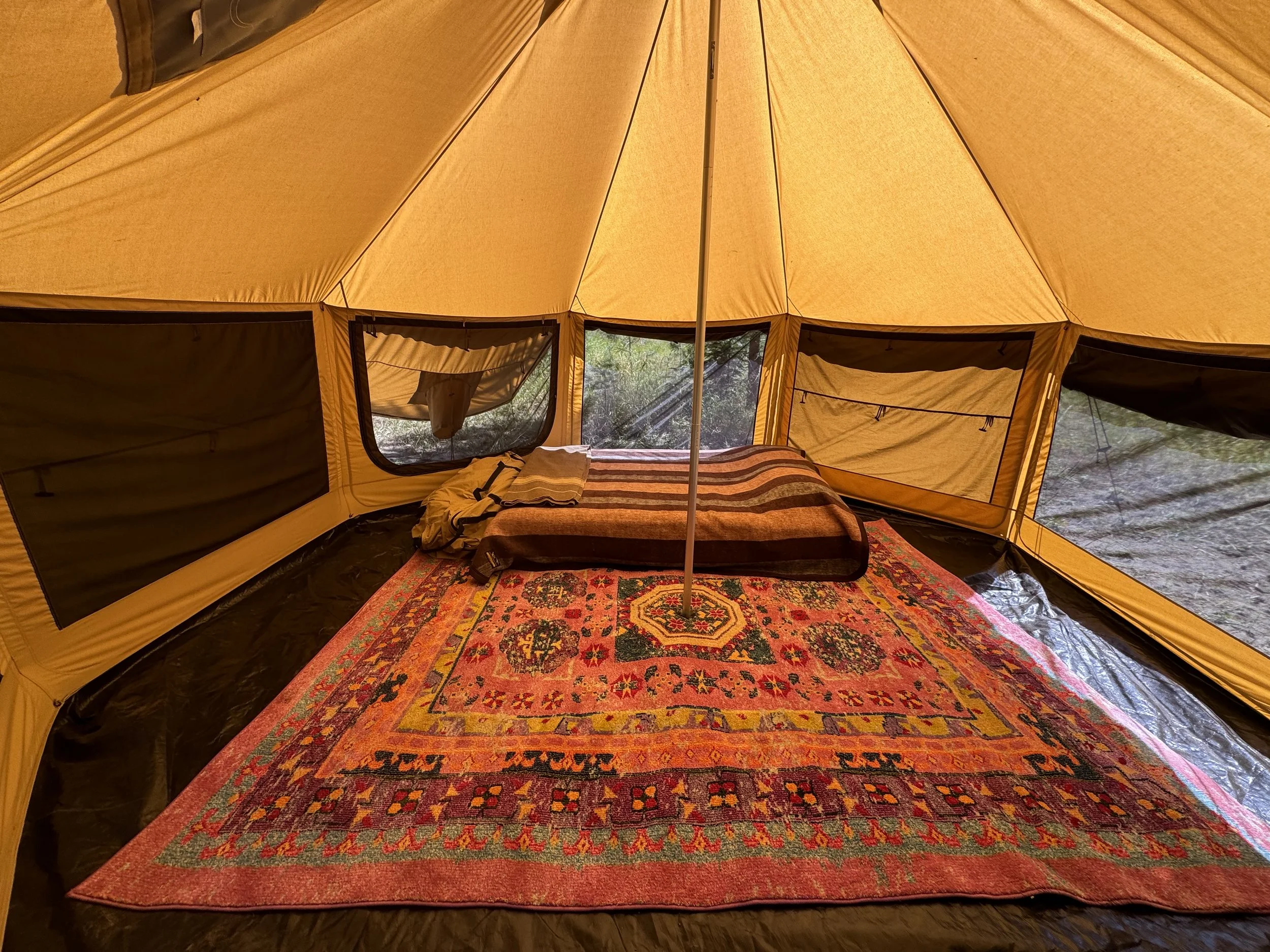The spacious dome tent interior with a rug, comfortable mattress, bedding, electricity via a power box and lots of windows.