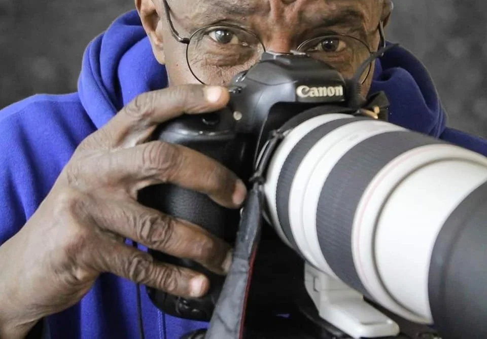 A person taking a photo with a professional Canon camera with a large telephoto lens