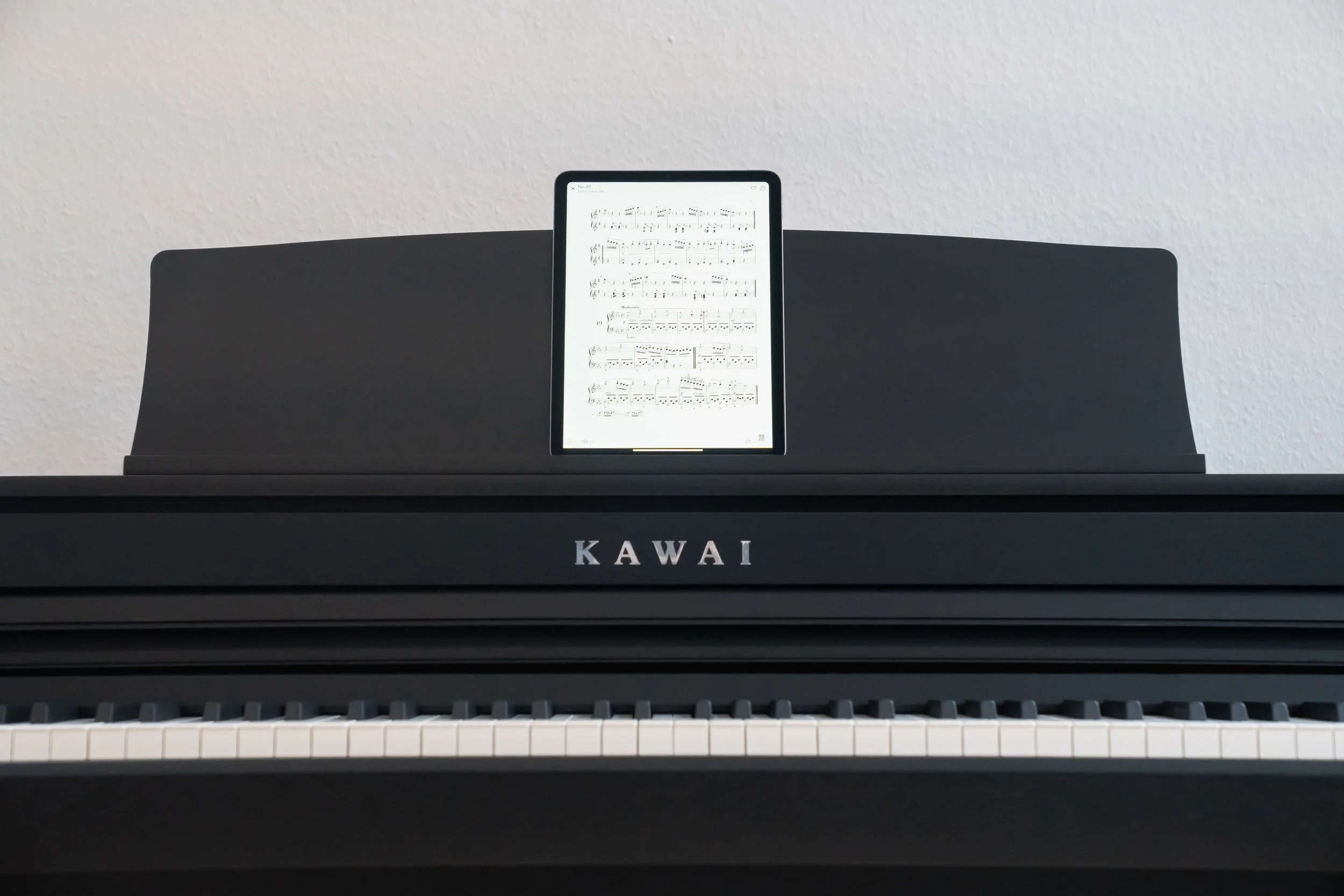 KAWAI CA401 front view of keyboard and ipad displaying sheet music resting on music desk. 