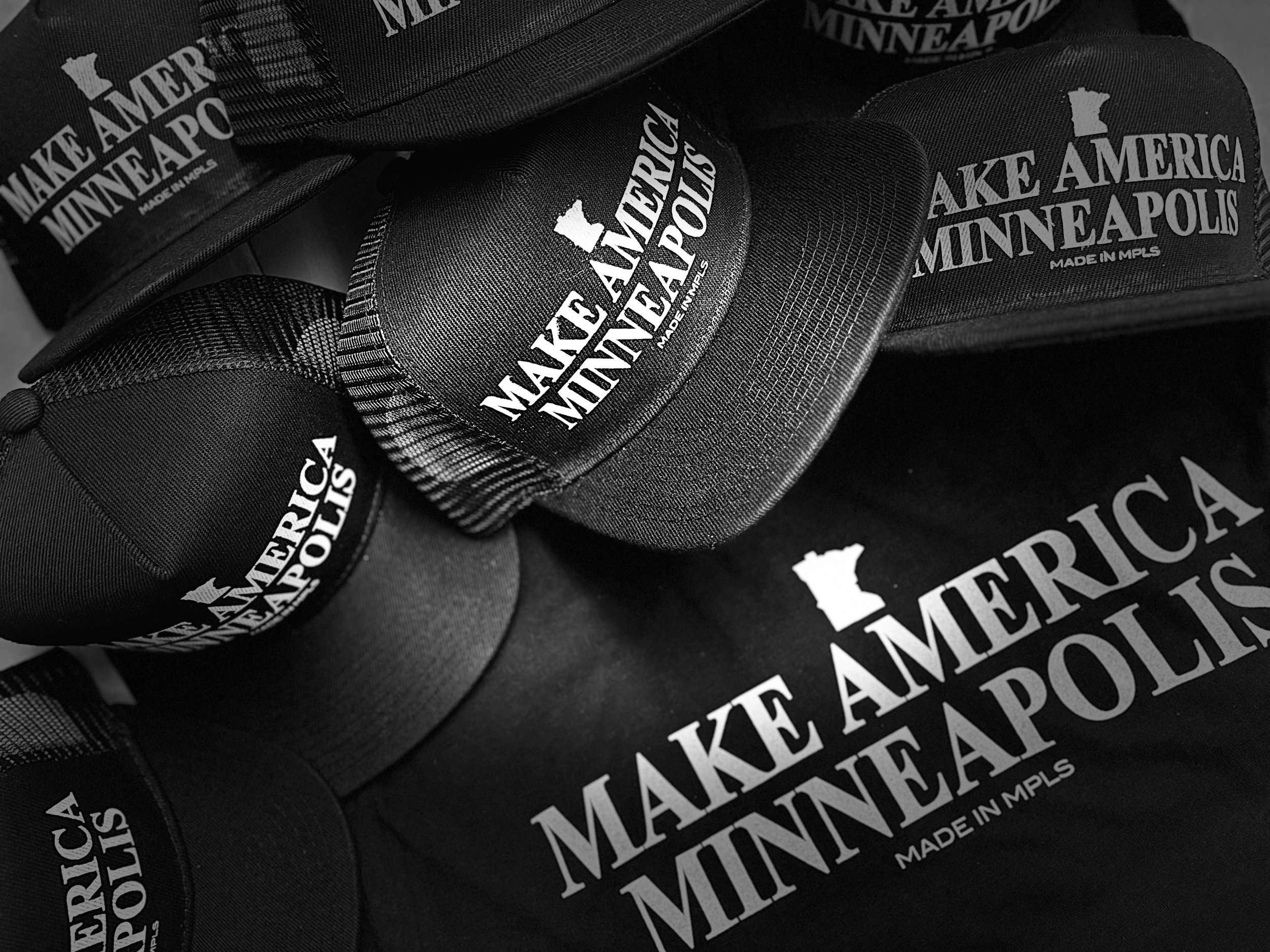 Black caps and a black tote bag with 'Make America Minneapolis' logo printed in white.