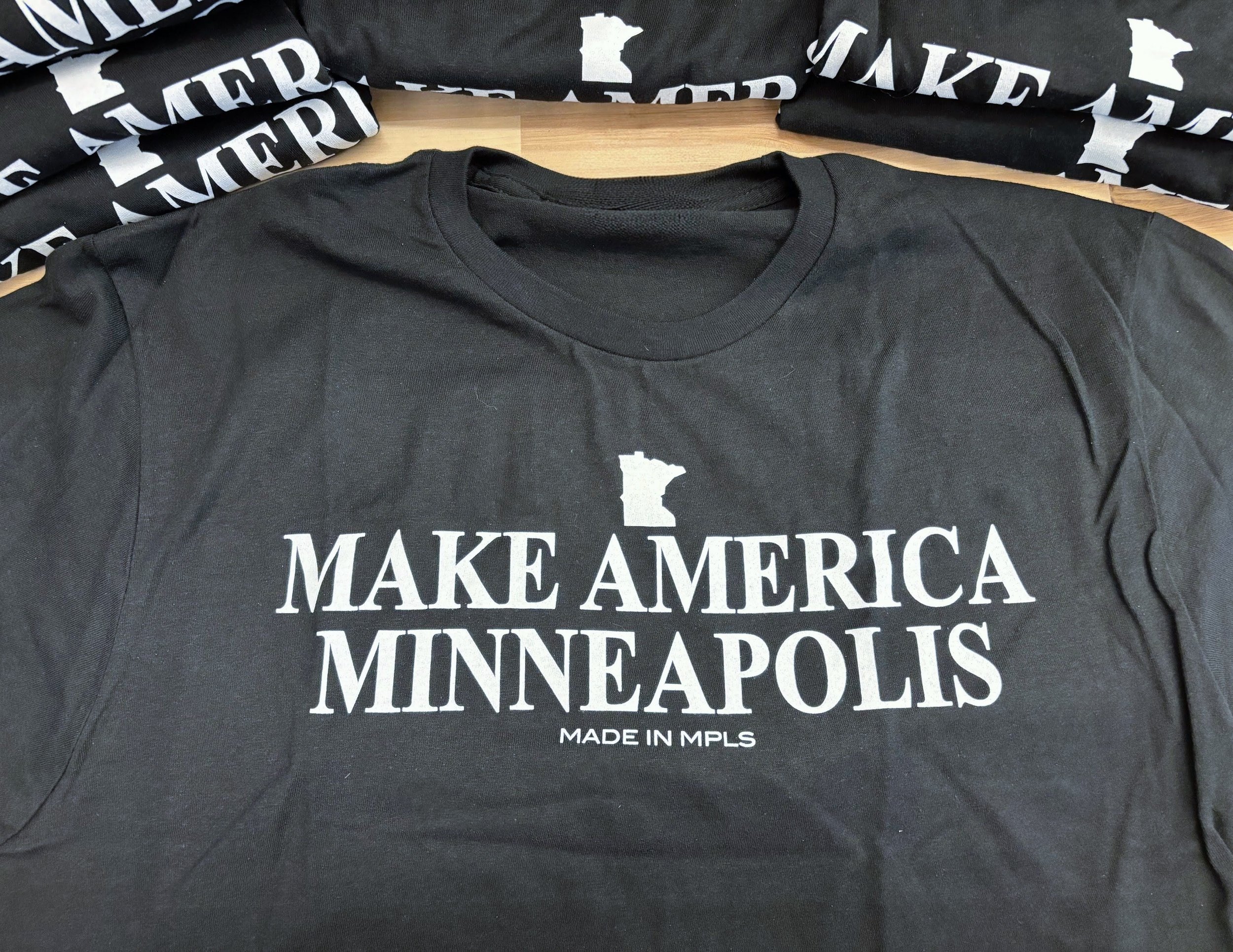 A black unisex t-shirt with Make America Minneapolis printed on it in white ink