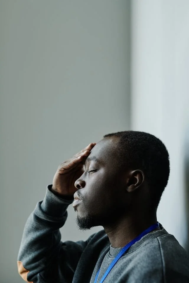 man with closed eyes and hand on forehead