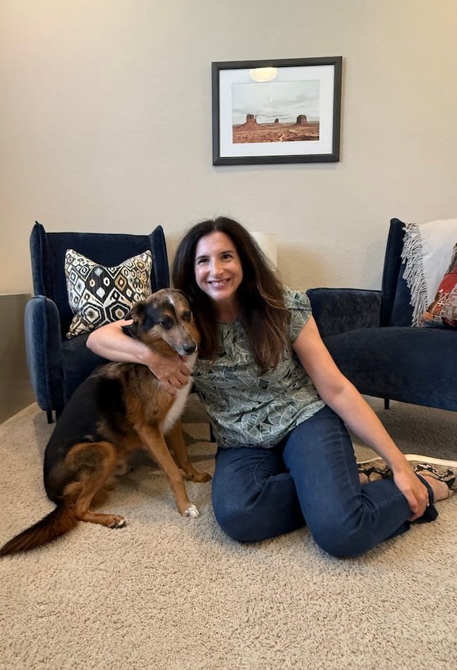woman with brown hair hugging a brown and black dog