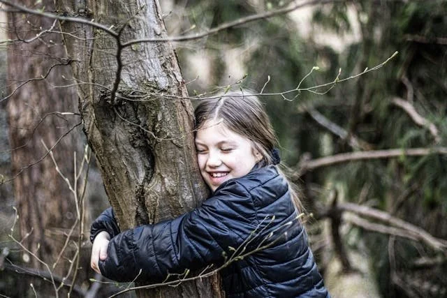 young girl hugging a tree trunk