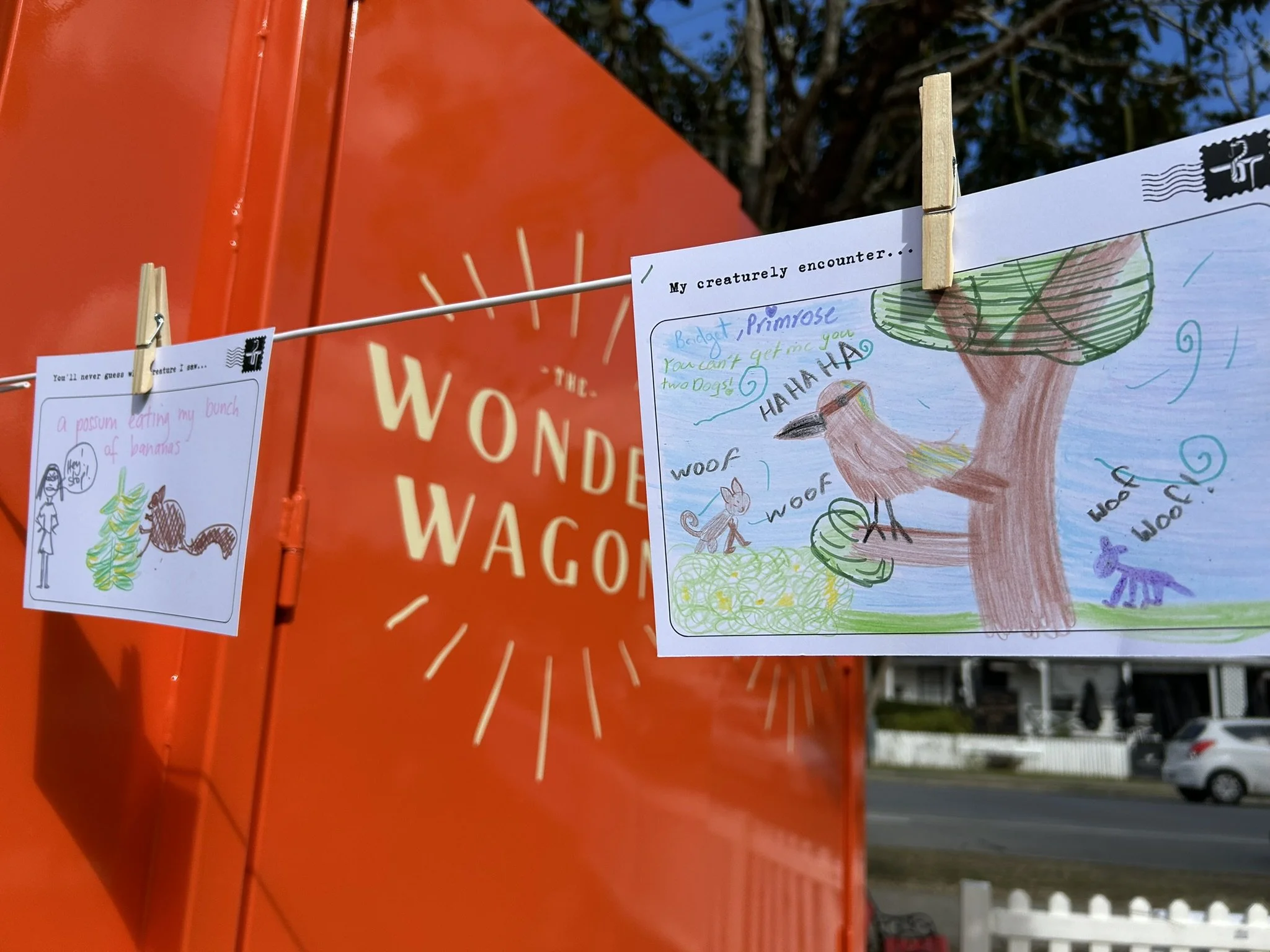 Colorful children's drawing of a bird sitting on a tree branch, with animals on the ground, and speech bubbles with sound effects like 'woof' and 'ha ha ha', and handwritten notes.