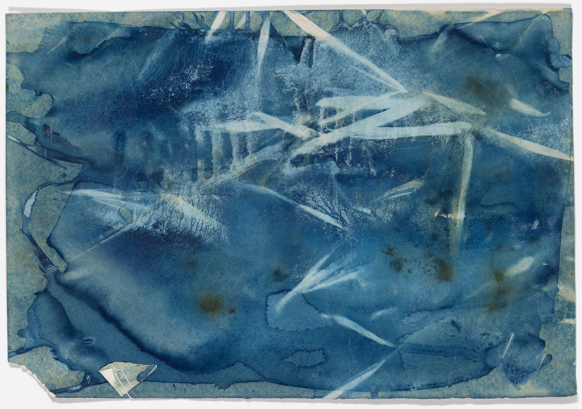 A piece of paper with blue abstract watercolor paint and white streaks, with torn edges and some dark stains.