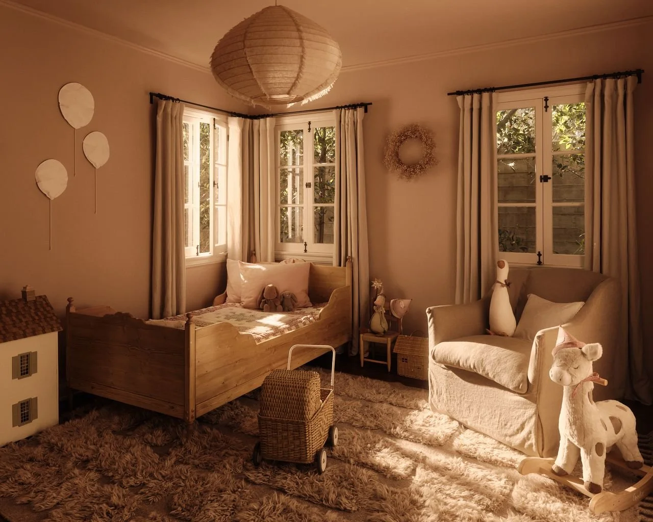 Cozy children's bedroom with beige walls, large windows with cream curtains, a wooden toddler bed with stuffed animals, a white rocking horse, a plush armchair with a pillow, and warm sunlight through the windows.