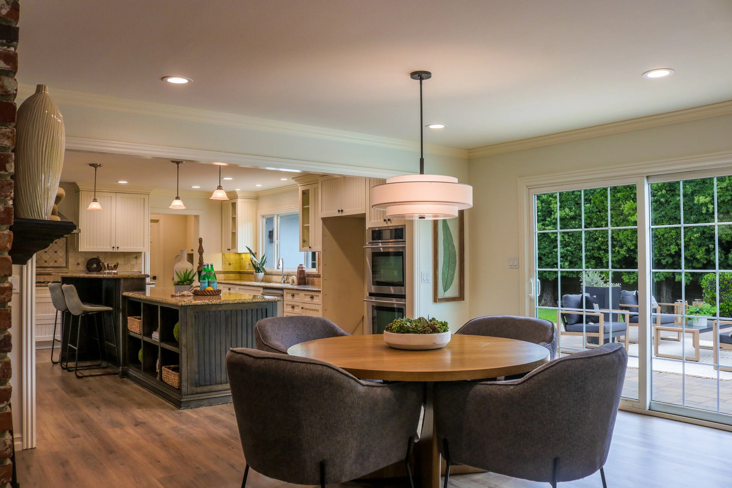 Open-concept kitchen and dining area with large windows, sliding glass door leading outside, and modern decor.