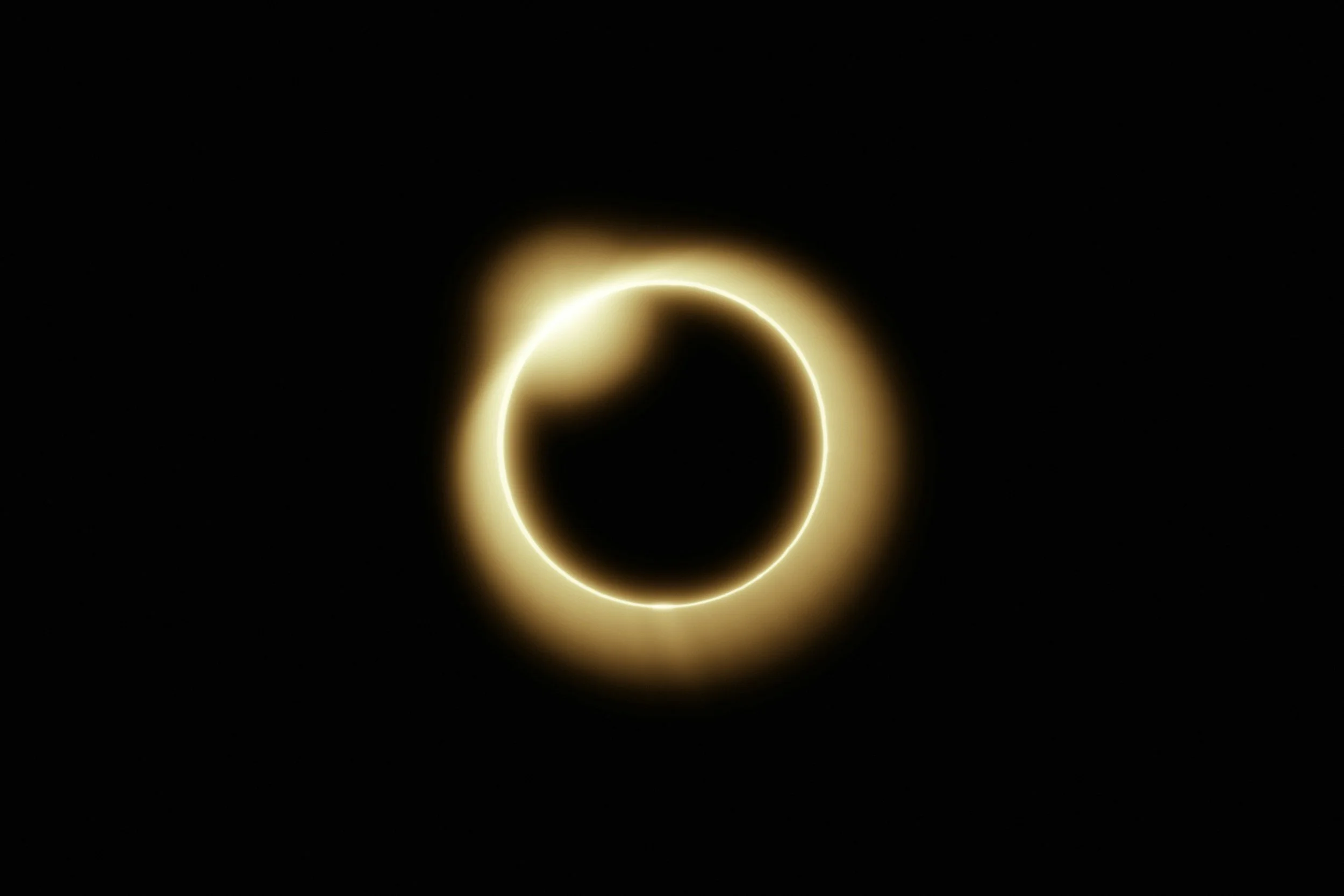 A solar eclipse with the moon covering the sun, creating a glowing ring of light around the dark moon.