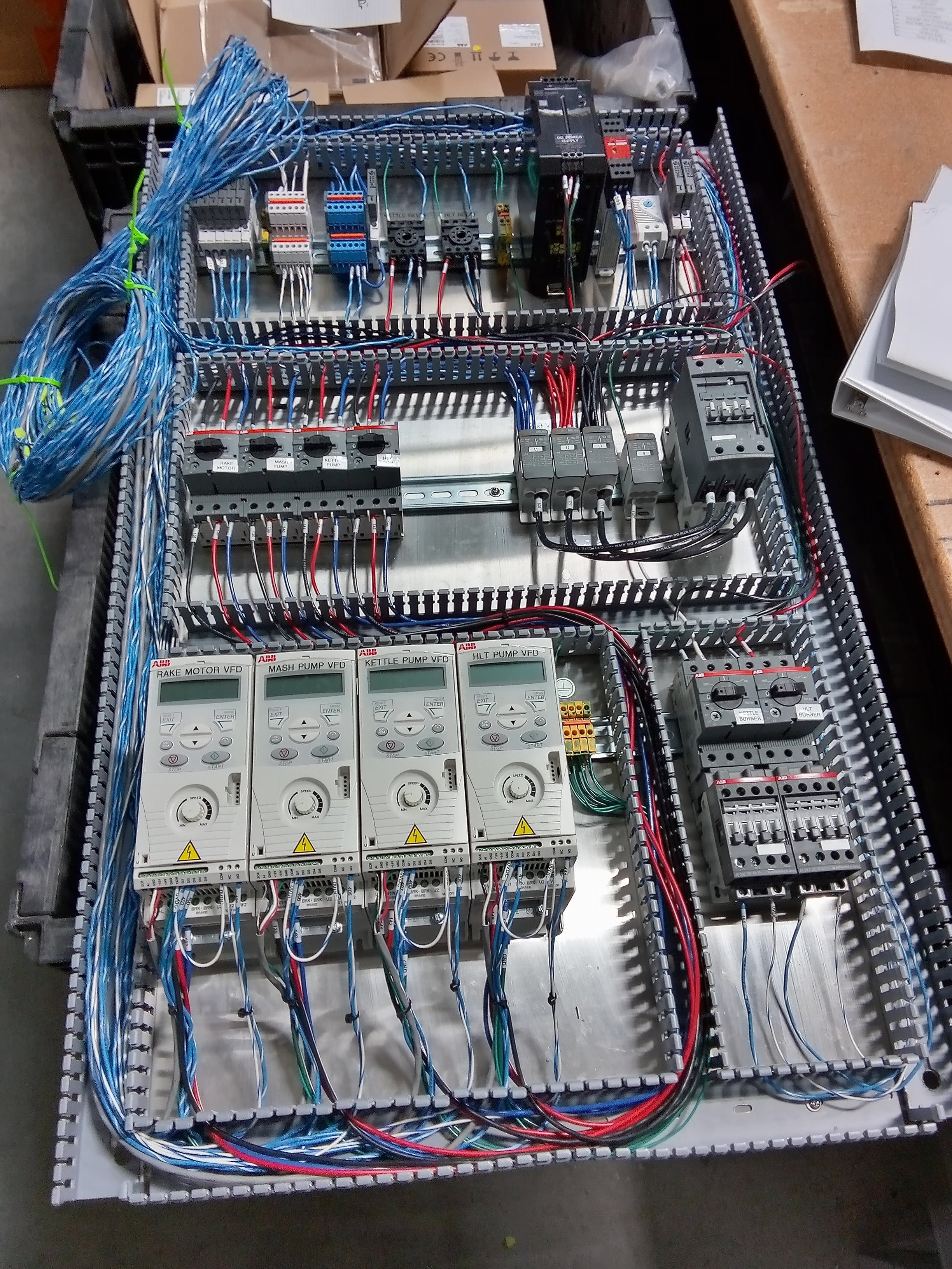 A large industrial control panel with various wiring, circuit breakers, and digital controllers for machinery.