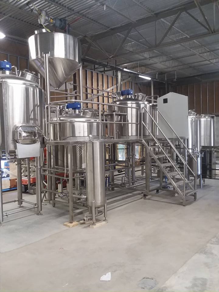 Industrial stainless steel equipment in a manufacturing facility, including tanks, pipes, and stairs.