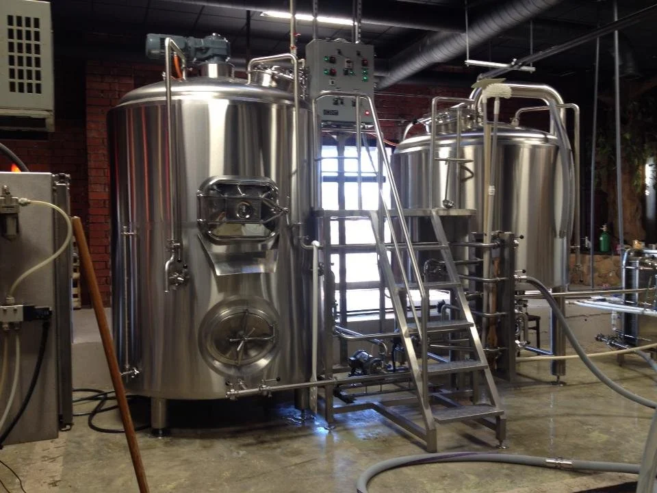 Stainless steel brewing tanks with ladders in a brewery or industrial facility.