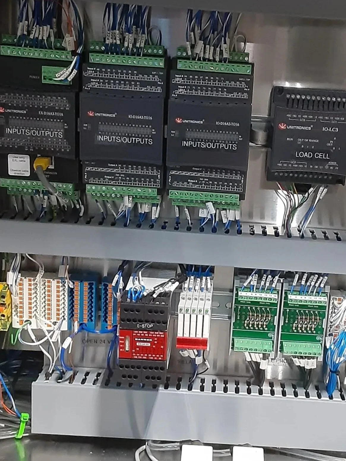 Electrical control panel with various black, green, white, orange, and red components, wiring, and connection terminals.