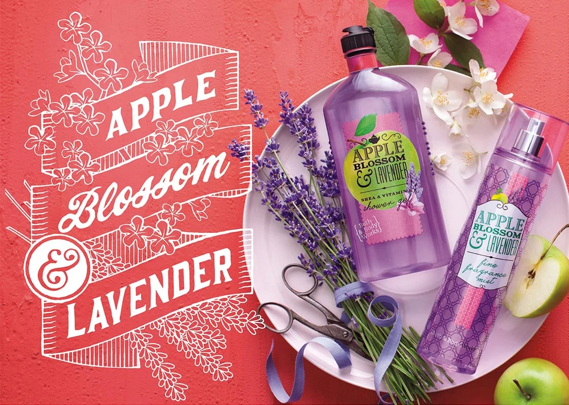 A white plate with a bunch of lavender and apple blossom flowers, a lavender shower gel bottle, a lavender spray bottle, a cut green apple, and decorative scissors on a pink surface with a pink background and white flower illustrations.
