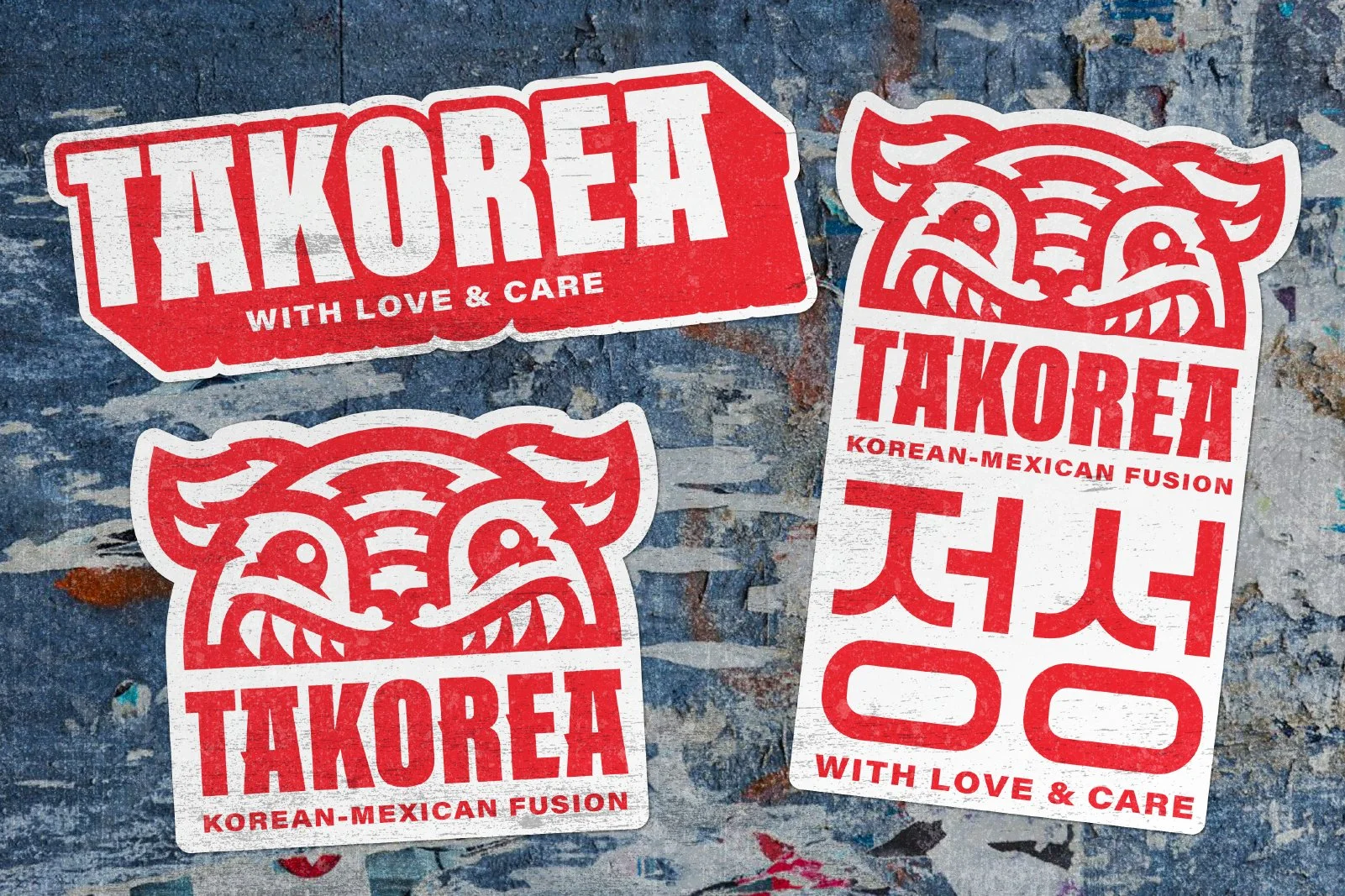 Four red and white stickers on a textured blue background. One sticker says 'TAKOREA WITH LOVE & CARE'. Two stickers feature a stylized, fierce, cartoonish tiger face with the words 'TAKOREA' underneath, and one sticker says 'TAKOREA KOREAN-MEXICAN F