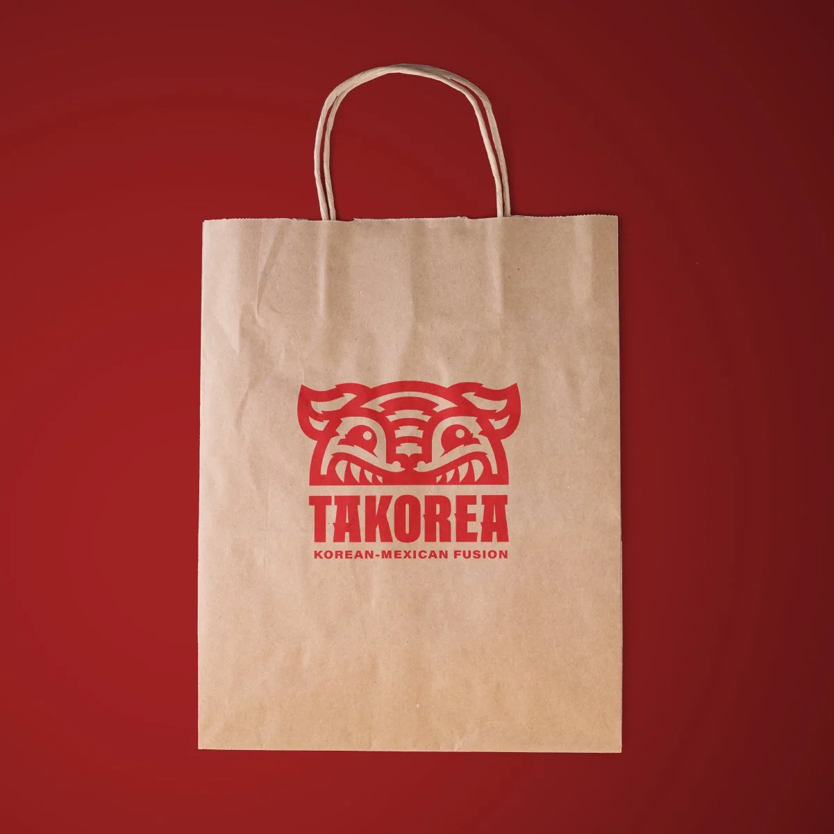 Brown paper bag with red Takorea logo and text, on a red background.