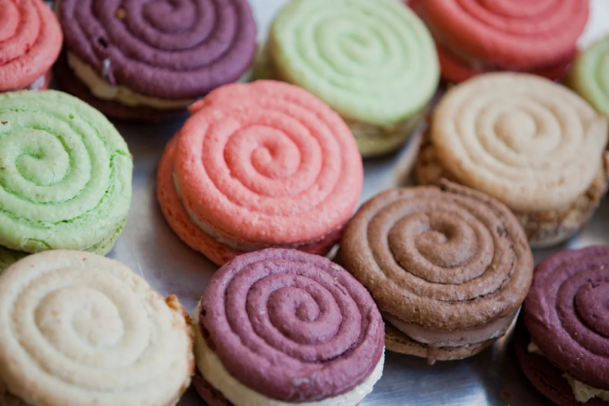Colorful swirl-patterned cookies in various pastel shades including pink, green, purple, beige, and brown, arranged in a close-up view.