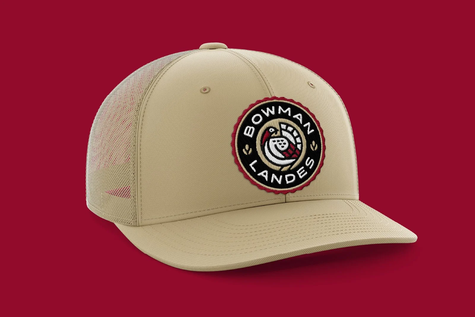 Beige baseball cap with Bowman Lands logo embroidered on front, set against red background.