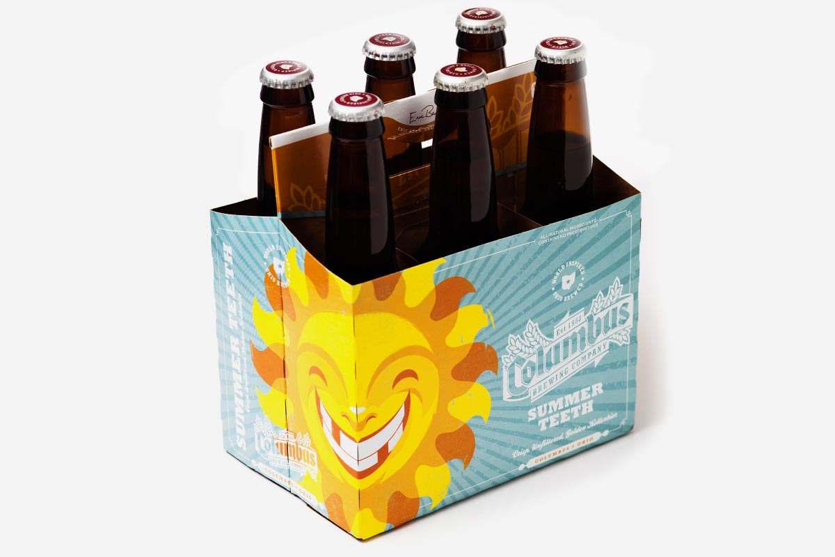 A six-pack of Dachaus Summer Teeth beer bottles with colorful packaging and a smiling sun illustration.