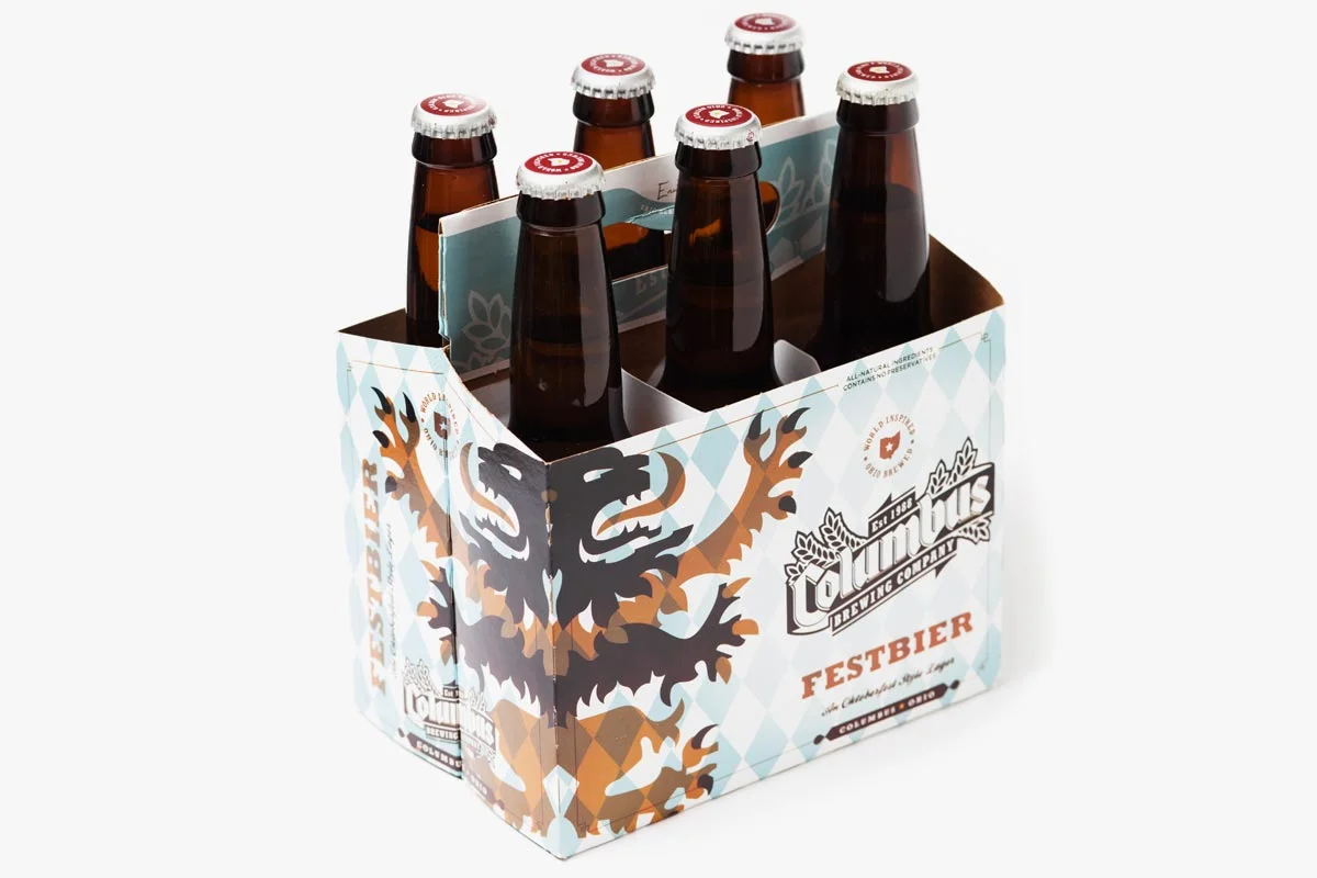 Six bottles of Festbier beer in a six-pack carrier with a stylized lion design and brewery branding.