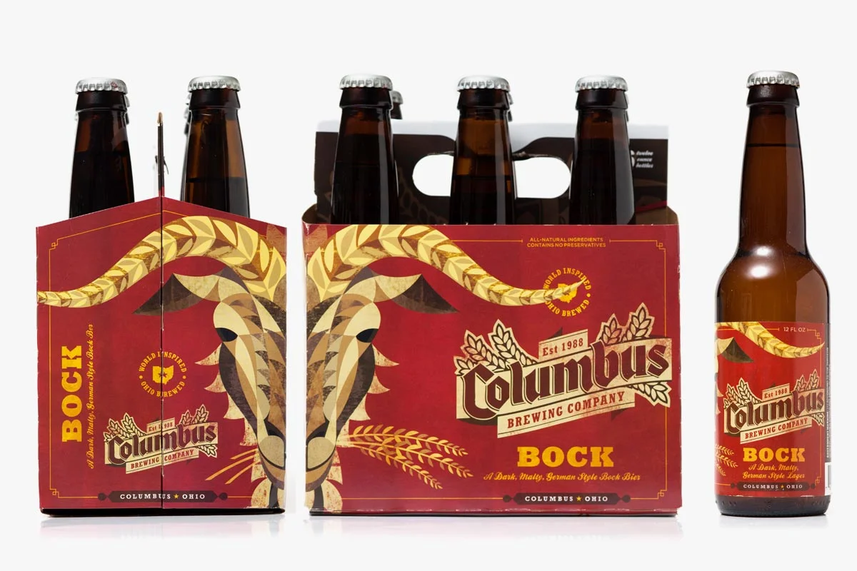 Six bottles of Columbus Brewing Company's Bock beer, five in a six-pack carrier and one bottle beside it, featuring a red label with a stylized goat's face and wheat graphics.