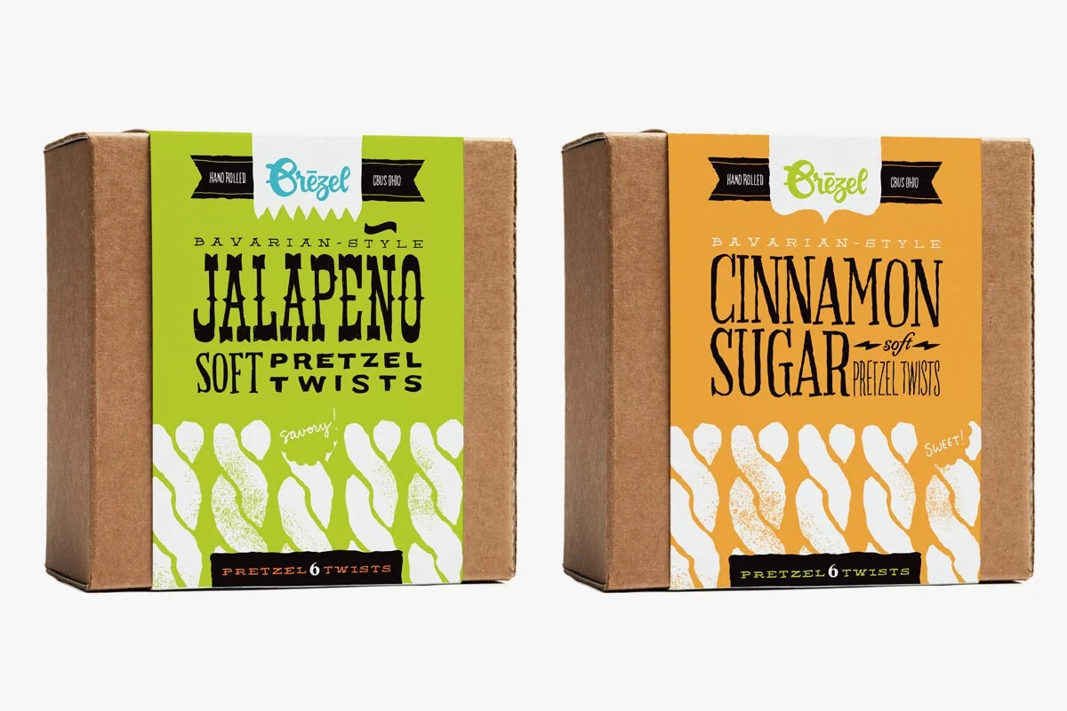 Two boxes of Bavarian-style pretzel twists; one with jalapeno flavor and the other with cinnamon sugar flavor; both hand-rolled and labeled with colorful packaging.