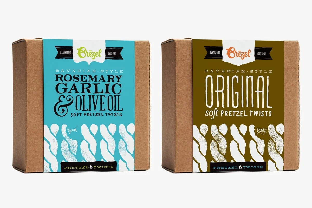 Two boxes of Bavarian-style pretzel twists. The box on the left is labeled rosemary garlic and olive oil, and the box on the right is labeled original. Both are hand rolled and contain six pretzels each.