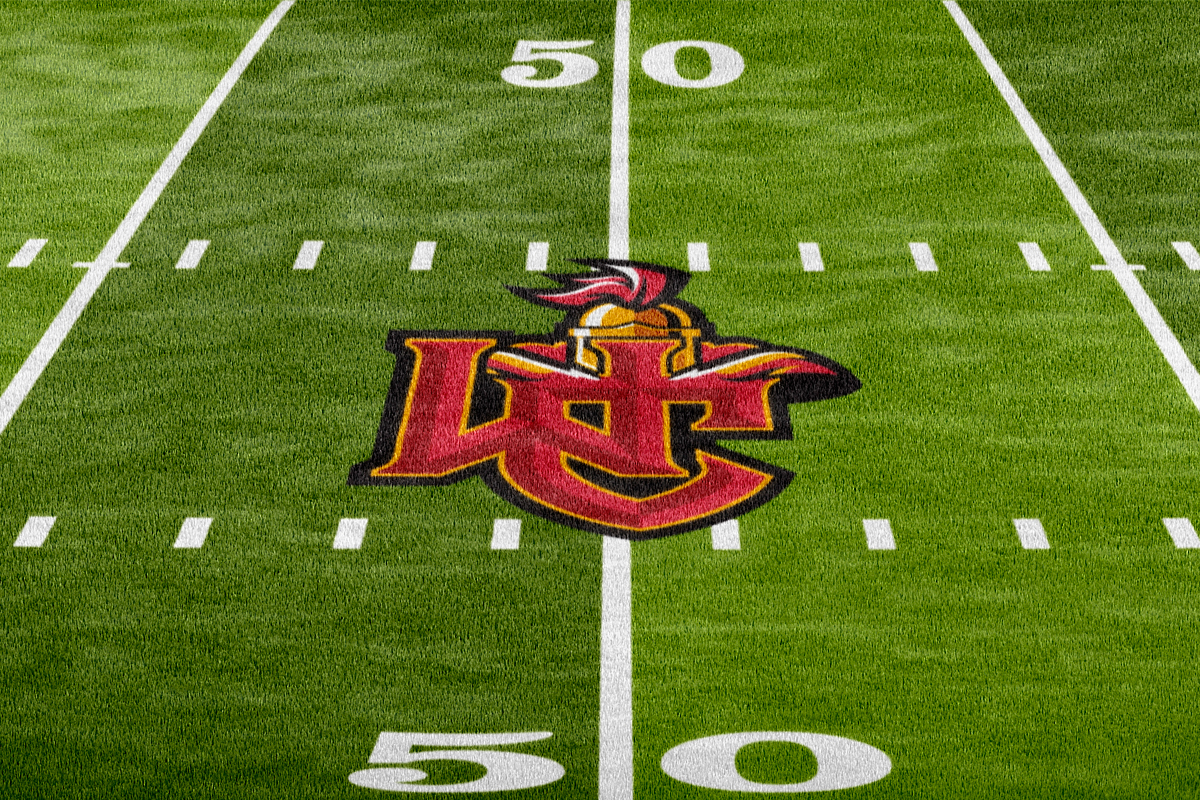 A football field with a logo of the Baltimore Ravens team at the center.