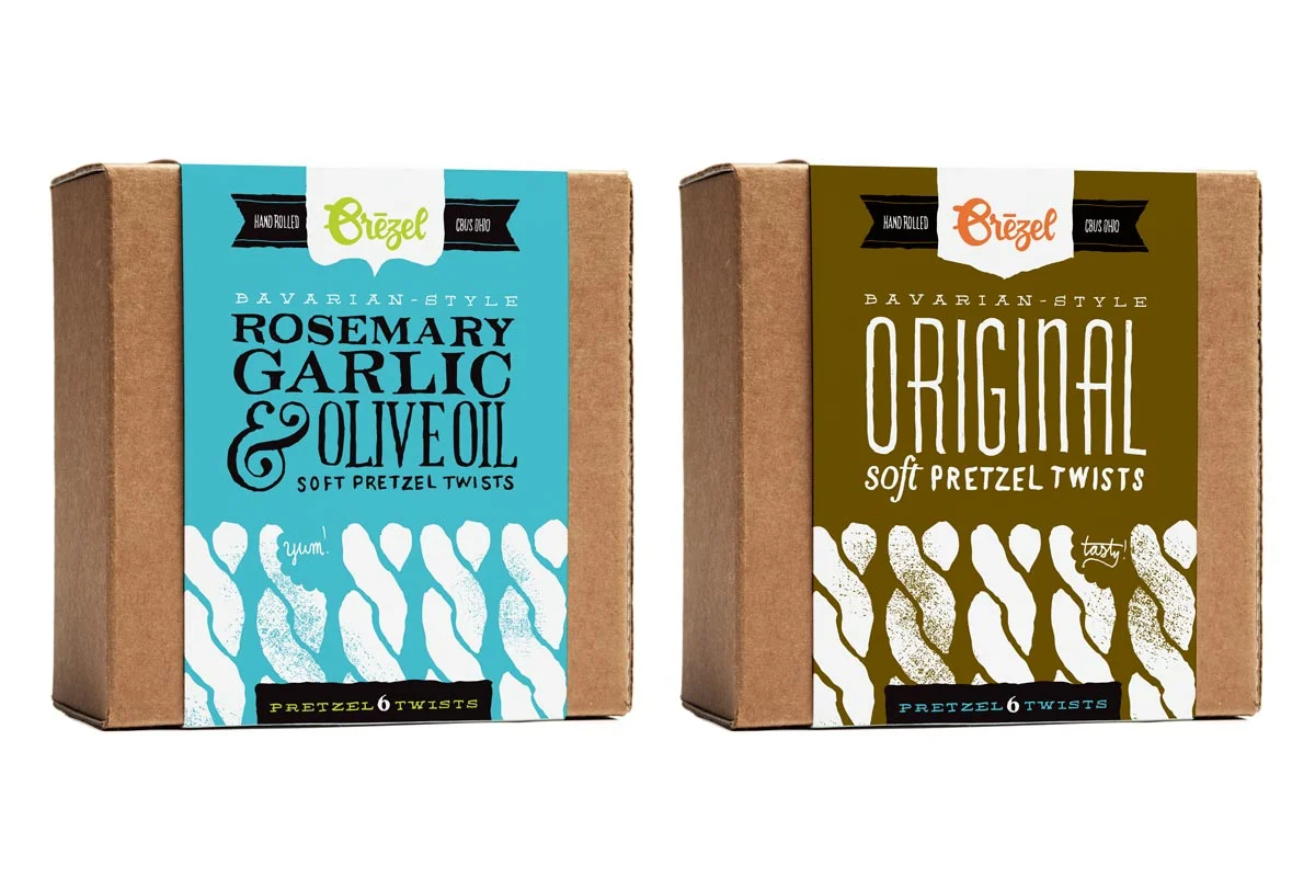 Two boxes of Bavarian-style soft pretzel twists from Brezel. The left box is rosemary, garlic, and olive oil flavor with a blue label. The right box is original flavor with a brown label.
