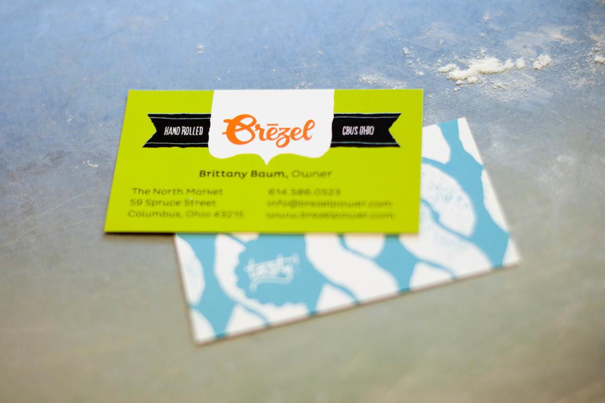 Close-up of a bright green business card on a light blue patterned business card with a white and blue design underneath.