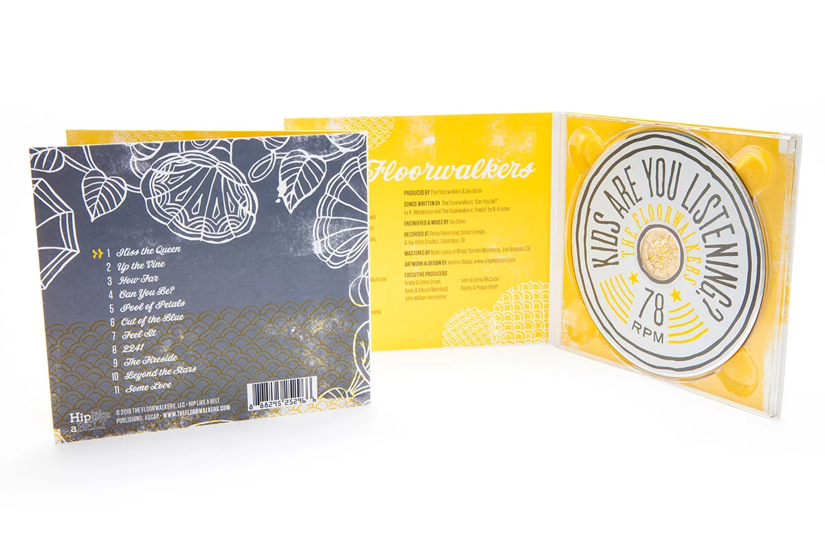 Open CD case with a yellow and white design, featuring a list of song titles on the inside left, and a circular logo with text on the right that reads 'Who Are You Listening To? The Floor Walkers, 78 RPM'.
