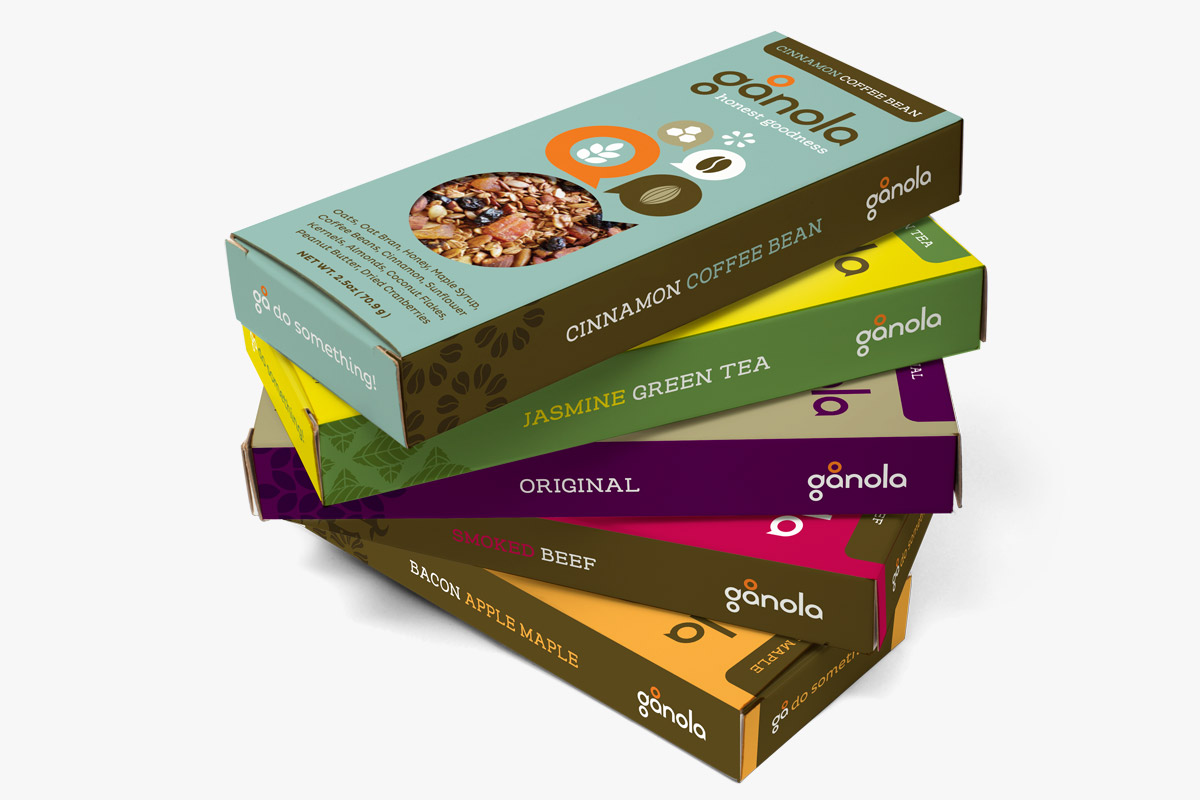 Stack of five boxes of tea and coffee products in colorful packaging from the brand 'ganola', including cinnamon coffee bean, jasmine green tea, original, smoked beef, and bacon apple maple flavors.