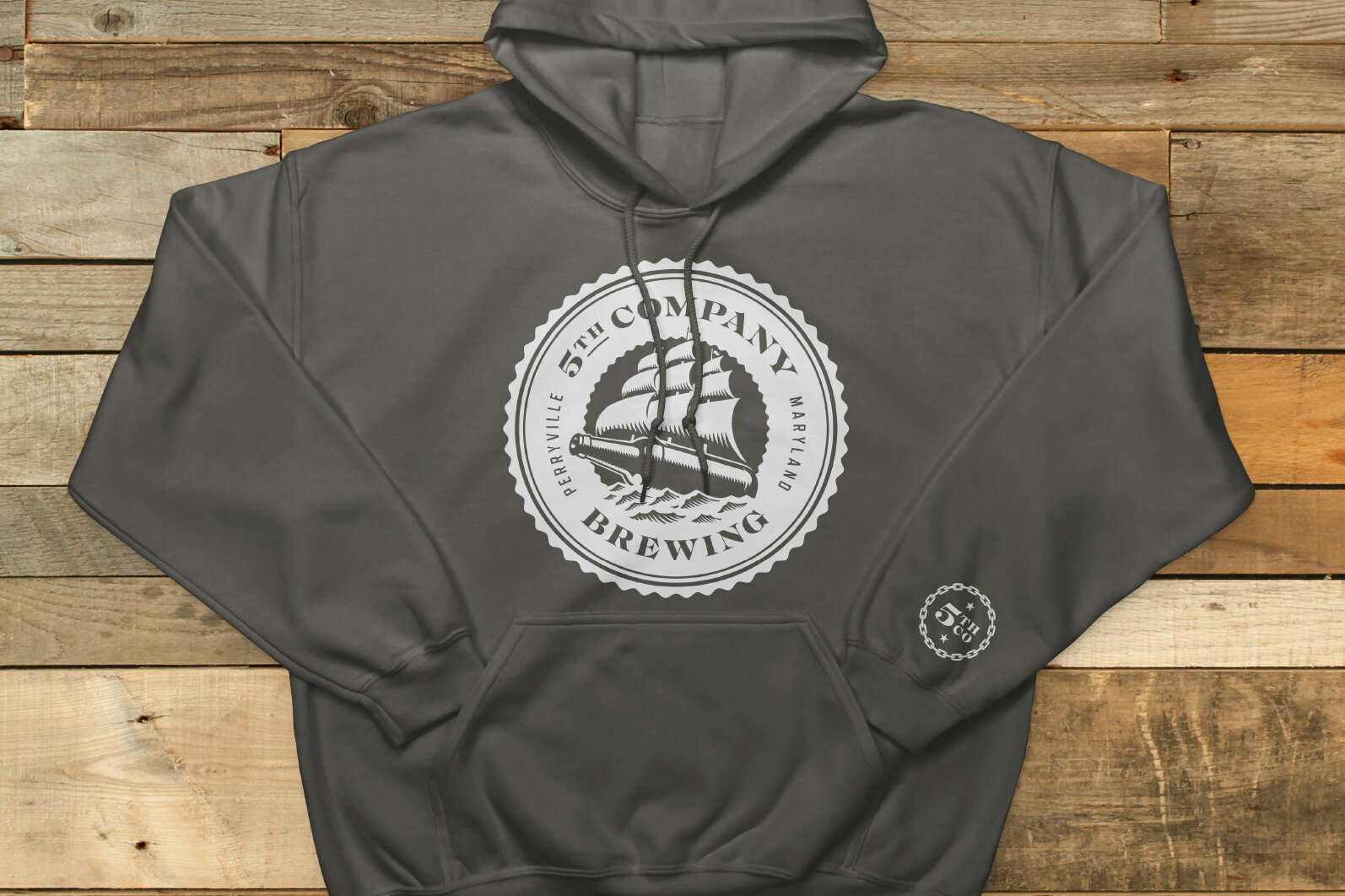 Gray hoodie with a circular logo on the front reading '15th Company Brewing,' featuring a sailing ship, and a smaller logo on the sleeve.